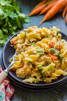 a plate of pasta with broccoli and carrots next to some canned food