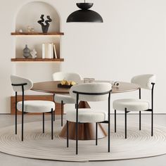 a round table with four chairs and a vase on the wall behind it in a white room