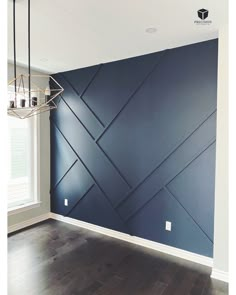 an empty room with blue walls and wood flooring in the center is a chandelier