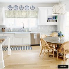 a kitchen with white cabinets and wooden floors, an island table surrounded by chairs in the center