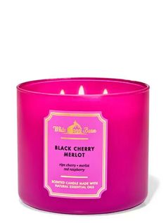 black cherry merlot candle in a pink glass container with two lit candles on top