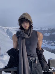 a young man standing on top of a snow covered slope next to a wooden fence