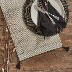 a place setting with black napkins and silver utensils on a wooden table