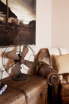 a living room with a couch, fan and painting on the wall next to it