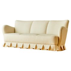 a cream colored couch with ruffles on the arms and back, against a white background