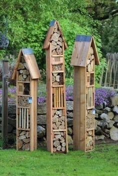 three wooden structures made out of logs in the grass