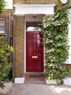 a red door with ivy growing up the side of it