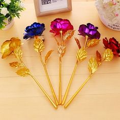 five different colored flowers sitting on top of a wooden table