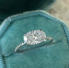 a diamond ring sitting on top of a blue velvet cushion in a green velvet case