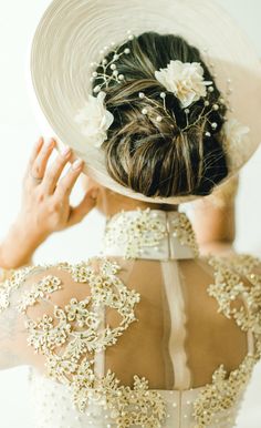 a woman wearing a white hat with flowers on it's back and her hair in a bun