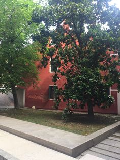 a red building with steps leading up to it and trees in the front yard area