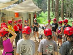 a group of people wearing red helmets standing in the woods