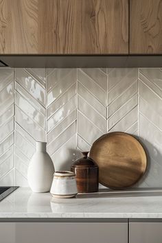 a kitchen counter with white tiles and wooden accents on the backsplash, along with two vases