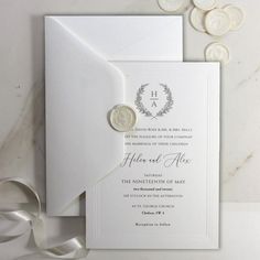 a white wedding card with a wax seal on it and some silver coins around it