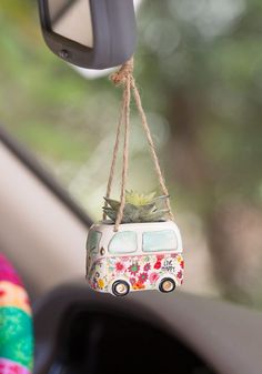 a mini van hanging from the side of a car with flowers on it's roof