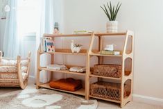 a wooden shelf with baskets on it next to a baby crib in a room