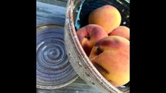 a bowl filled with peaches sitting on top of a wooden table