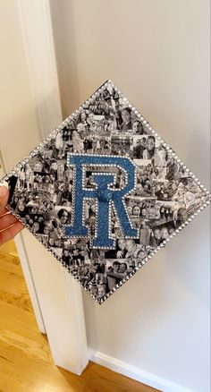 a person holding up a graduation cap with the letter r on it in front of a door