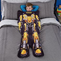 a young boy laying in bed with a pillow shaped like a bumblebee character