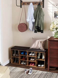 a coat rack with shoes and coats hanging on it next to a dresser in a living room