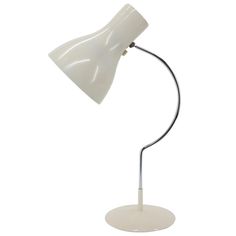 a white table lamp with a metal base and a light bulb on the top of it