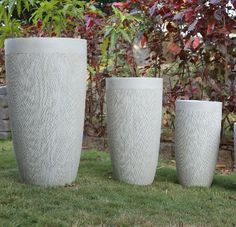 three large white vases sitting in the grass