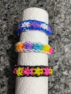 four different colored bracelets sitting on top of a roll of toilet paper next to each other