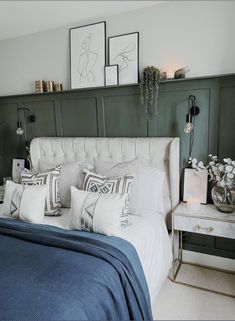 a bed with blue sheets and white pillows in a bedroom next to two pictures on the wall