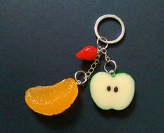 two pieces of fruit are attached to a metal keychain on a black surface