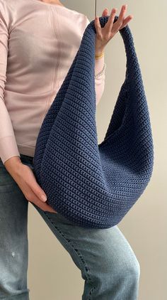 a woman holding an umbrella over her shoulder in blue crocheted material, with one hand on top of the other