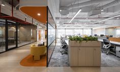 an office with glass walls and plants in the center, along with yellow chairs on either side