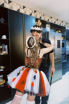 a man and woman dressed up in costumes standing next to each other on the kitchen floor