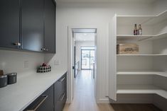 an empty kitchen with white walls and wooden flooring is seen in this image from the hallway to the dining room