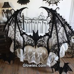 a black bat bed with white lace on it's sides and bats hanging from the headboard