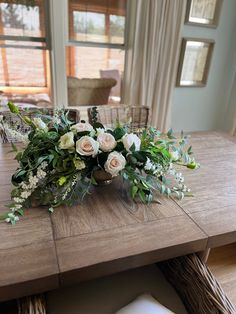 a wooden table topped with white flowers and greenery