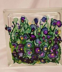 a glass block with purple and green flowers in the center, on a white background