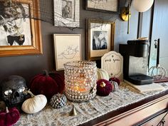 a table topped with lots of halloween decorations next to framed pictures and candles on top of it