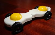 a toy car with two eggs on the front wheels sitting on a wooden table top