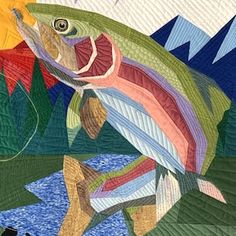 a colorful fish is depicted on a quilted wall hanging in front of a black cat