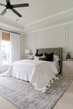 a large white bed sitting in a bedroom on top of a blue and white rug