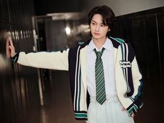 a young man wearing a green and white striped tie standing in front of a metal wall