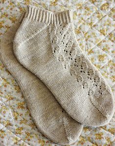 two pairs of knitted socks sitting on top of a floral print bed spreader