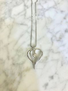 Metal: 14kt White Gold Stone: Diamond Stone Shape: Round Diamond Weight: .19 ctw Weight of Pendant with Diamond: 1.80 grams Dimensions Of Heart Including Bail: 26mm Long 18mm Wide Weight of Chain: 1.30 grams Type of Chain: 1mm Diamond Cut Cable Chain Type of Clasp: Spring Clasp Length of Necklace: 16 Inches. Other chains available. Customization: Can be custom made with any gems and metals. Silver Heart-shaped Diamond Necklace With Vvs Clarity, Silver Heart Diamond Necklace With Vvs Clarity, Sterling Silver Heart Necklace With Vvs Clarity, Elegant Heart Necklace With Prong Setting For Anniversary, Elegant Heart Necklace With Prong Setting For Valentine's Day, Elegant Prong-set Heart Necklace For Valentine's Day, Sterling Silver Heart Pendant Diamond Necklace With Brilliant Cut, Sterling Silver Open Heart Diamond White Necklace, Classic Silver Heart-shaped Diamond Necklace