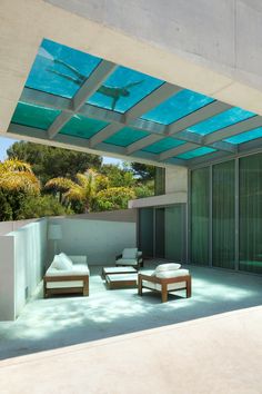 an outdoor living area with furniture under a glass roof