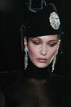 a woman wearing a black hat and veil with diamond decorations on it's head