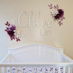 a white crib with purple and white flowers on the wall above it that says, choe lin