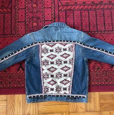 "Welcome to my collection of upcycled clothing! :) Every piece is made with items thrifted or upcycled for the purpose of creating sustainable pieces and decreasing waste! Handmade and Upcycled Fabric and trims with Aztec patterns have been hand-sewn along with a layer of silver tone sequins to transform this denim jacket with a chic BOHO look!  SIZE: It says Kids XL but MAY easily fit a regular women's size 6-8 Chest: 36\" Sleeve Length: 21\" Shoulder: 16.5\" Jacket Length: 22\" Care Instructions: This garment has handsewn details. I recommend gentle hand washing with mild detergent. DO NOT SOAK for more than 15 minutes in cold water. Do not wash with fabric softener or bleach. Lay flat or hang dry. Iron on the reverse side." Bohemian Embroidered Outerwear In Medium Wash, Bohemian Denim Jacket With Pockets In Medium Wash, Bohemian Embroidered Denim Outerwear, Bohemian Embroidered Cotton Denim Jacket, Bohemian Medium Wash Cotton Outerwear, Custom Jean Jacket, Upcycled Denim Jacket, Horseshoe Decor, Upcycled Fabric