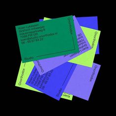 several business cards stacked on top of each other in blue, green, and purple