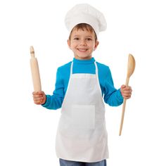 a young boy in an apron holding two wooden spoons and a rolling pin on his left hand