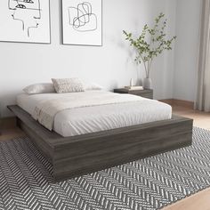 a large bed sitting on top of a wooden floor next to two pictures above it